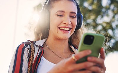 Frau mit einem Smartphone in der Hand und Kopfhörern